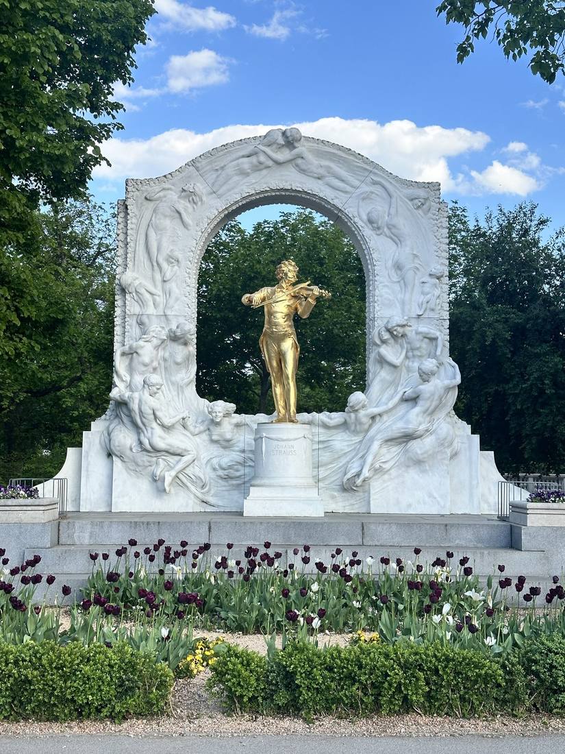 Gilded bronze Johann Strauss II in marble arch with spring tulips